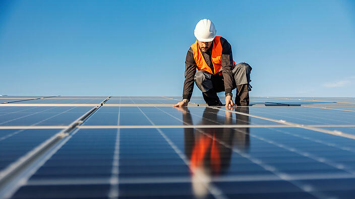 Facharbeiter bringt Solarpaneelen an 